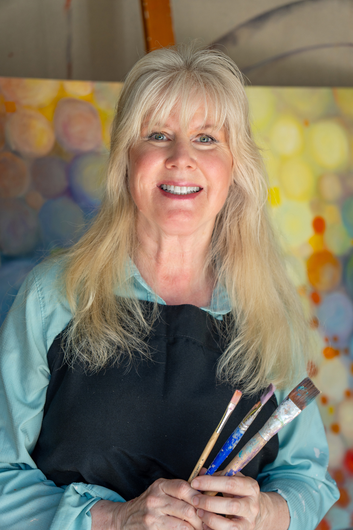 Trisha Selgrath in her studio holding paint brushes